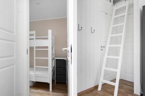 ein Schlafzimmer mit weißen Etagenbetten und einer Leiter in der Unterkunft Cute little cottage in Höllviken in Höllviken