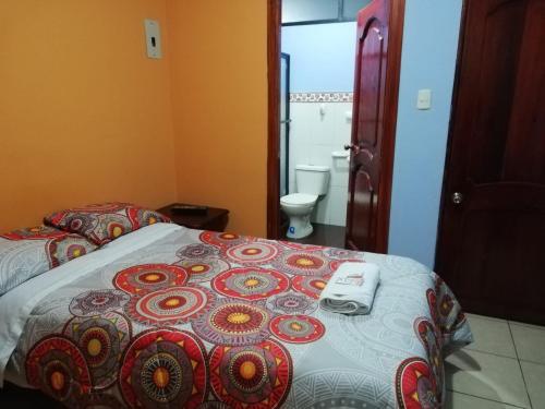 a bedroom with a bed and a bathroom with a toilet at Centro Macas in Macas