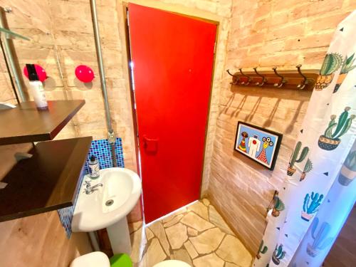 baño con puerta roja y lavamanos en Uma Casa Sobre o Mundo, en Santo Antônio do Pinhal