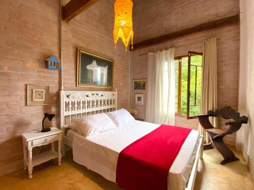 1 dormitorio con cama blanca y manta roja en Uma Casa Sobre o Mundo, en Santo Antônio do Pinhal