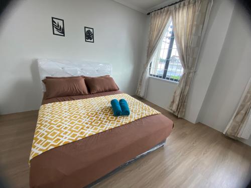 a bedroom with a bed with blue slippers on it at MAWAR HOMESTAY KUCHING in Kuching