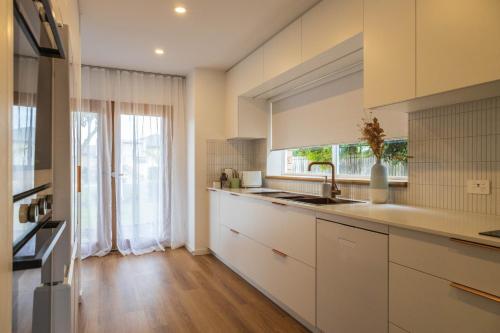 een keuken met witte kasten en een groot raam bij Bellvilla Suites in Merimbula