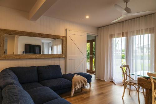 een woonkamer met een blauwe bank en een spiegel bij Bellvilla Suites in Merimbula