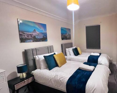a bedroom with two beds with blue and yellow pillows at HILLTOP PLACE SUITES M1 J31 near PEAK DISTRICT 