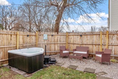 a backyard with a hot tub and chairs and a fence at NEW!! Lovely unit w/ PRIVATE Hot Tub and patio! in Laconia