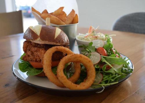 a plate with a hamburger and a salad and onion rings at Herons Mead Cottages in Orby