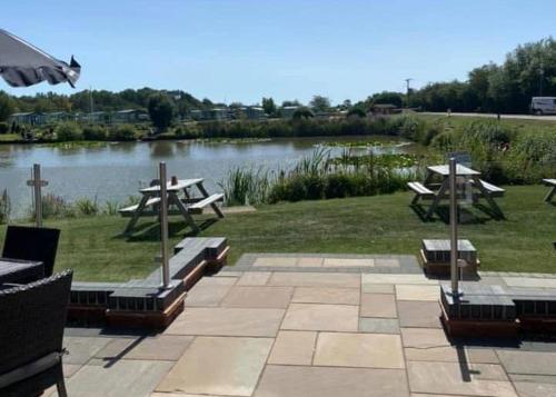 a picnic area with picnic tables and a body of water at Herons Mead Cottages in Orby