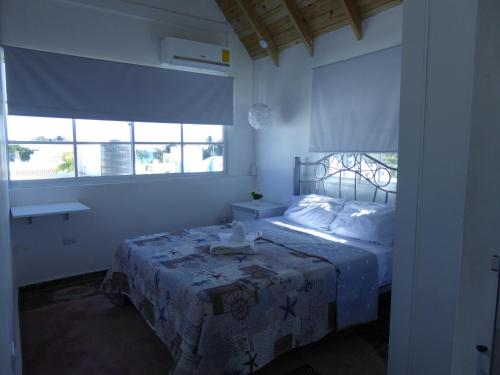a bedroom with a bed with a blue blanket and windows at CortLang - Beach Apartments - in El Pueblito near Playa Dorada in San Felipe de Puerto Plata