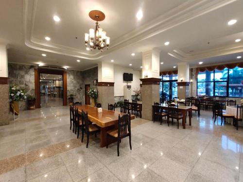 uma sala de jantar com mesas e cadeiras e um lustre em Golden Dragon Resort em Sing Buri