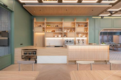 a kitchen with green walls and tables and chairs at Staybridge Suites Bangkok Sukhumvit by IHG in Bangkok