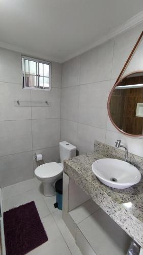 uma casa de banho branca com um lavatório e um WC em Casa Temporada Waldemar Damasceno - Beira Rio com piscina em Piranhas