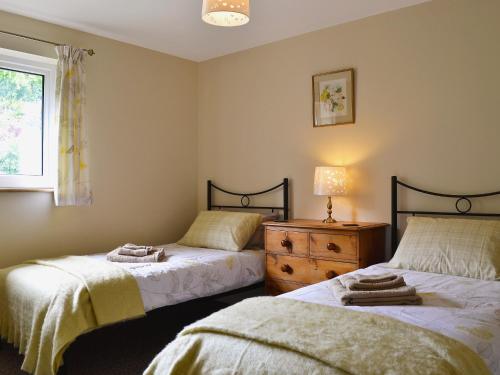 a bedroom with two beds and a dresser and a window at The Lodge in Presteigne