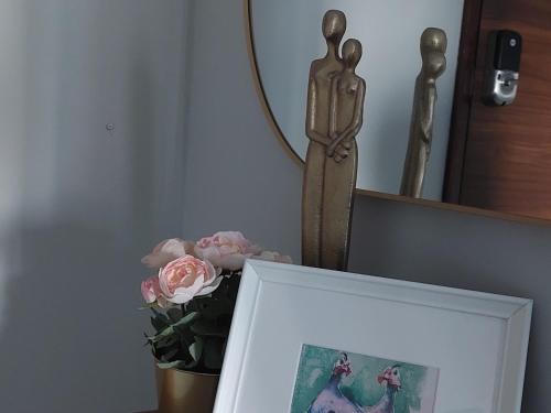 a picture frame with a vase of pink flowers and a statue at Superbly Modern and Airy Two Bedroom Seaside Apartment with Balcony in Bijilo