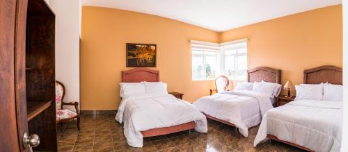 a bedroom with two beds and two chairs at CASA LOMA HOTEL BOUTIQUE & TERRAZA GASTRO in Popayan