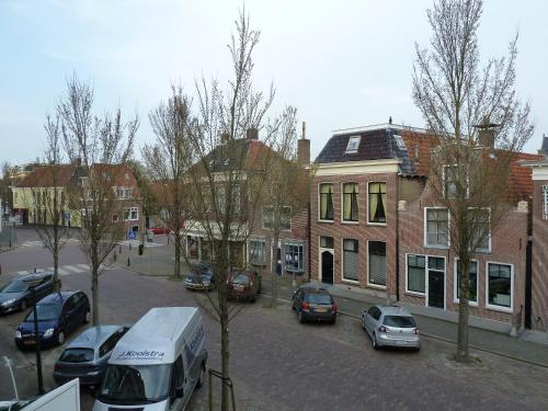 una strada di città con auto parcheggiate di fronte agli edifici di Hotel Centraal a Harlingen