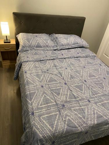 uma cama com um edredão e almofadas cinzentos e brancos em 1 Bedroom Modern Secondary Suite em Saskatoon