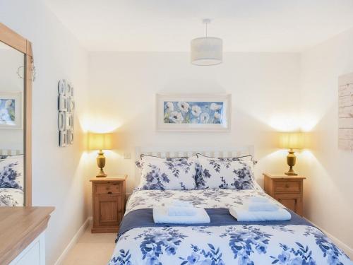 a bedroom with a blue and white bed with two lamps at Maple Lodge in Corsham