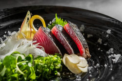 un plato negro de comida con sushi y verduras en KAMENOI HOTEL Kochi, en Ino