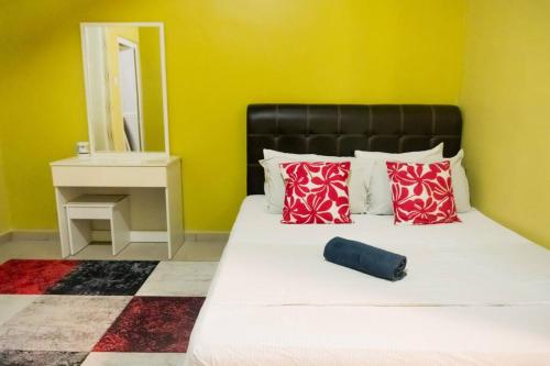 5 Bedrooms Homestay with Private Pool (SEROJA) في نيلاي: غرفة نوم بسرير ومخدات حمراء ومرآة