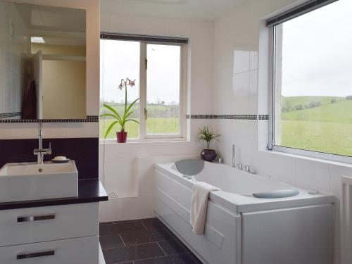 La salle de bains blanche est pourvue d'une baignoire et d'un lavabo. dans l'établissement Tan Y Castell, à Lampeter-Velfrey