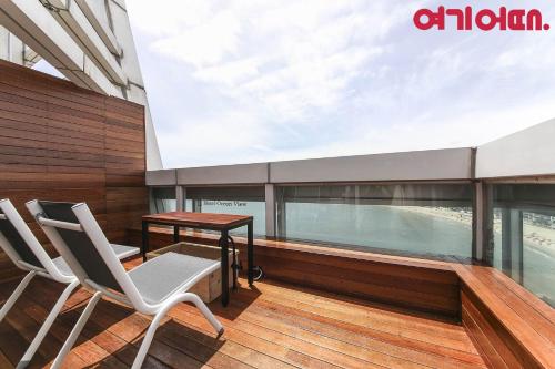 einen Balkon mit einem Tisch und Stühlen auf einem Gebäude in der Unterkunft Gwanganri HOTEL OCEANVIEW in Busan