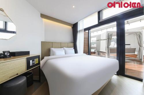 a bedroom with a large white bed and a desk at Gwanganri HOTEL OCEANVIEW in Busan