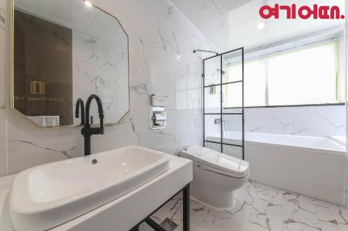 a white bathroom with a sink and a toilet at Gwanganri HOTEL OCEANVIEW in Busan