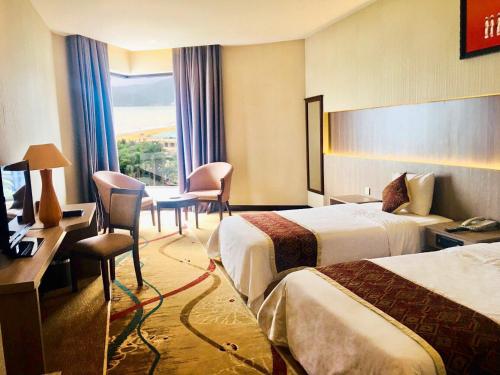 a hotel room with two beds and a desk at Saigon Quy Nhon Hotel in Quy Nhon