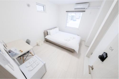 俱知安町JL HOUSE Kutchan的白色的小房间,配有床和桌子