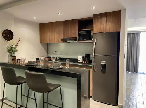 a kitchen with a bar with chairs and a refrigerator at BUSINESS SUITES MINE in Mexico City