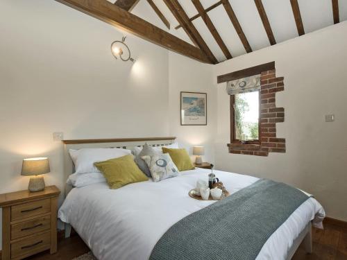 a bedroom with a large white bed and a window at Elm Tree Barn in Felmingham