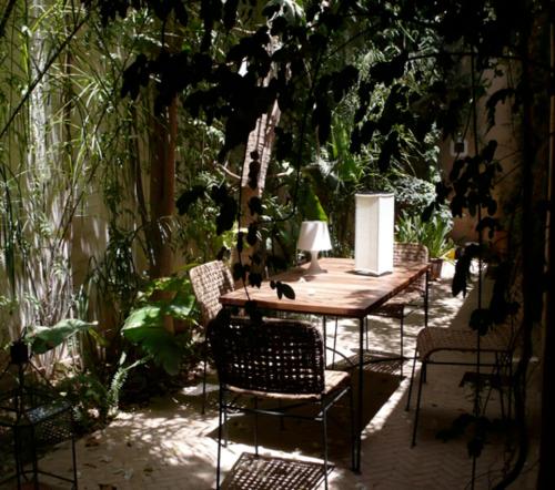 a wooden table and chairs in a garden at Dar Zahia in Taroudant