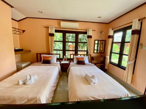 two beds in a room with two windows at Baanphuthadol in Mae Hong Son
