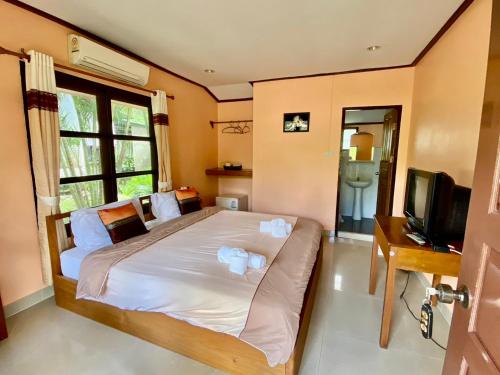 a bedroom with a bed with a television and a desk at Baanphuthadol in Mae Hong Son
