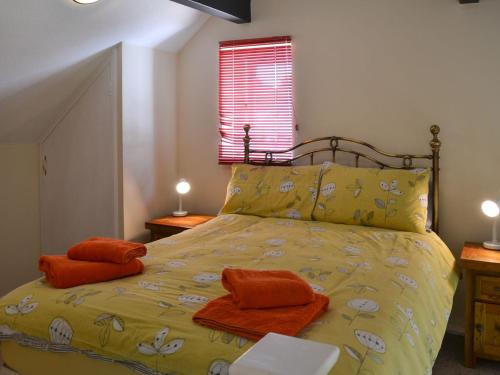 a bedroom with a yellow bed with orange towels on it at Puffin Cottage in Wroxham