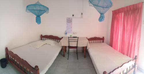 a room with two beds and a table in it at D.K. Rest inn in Embilipitiya