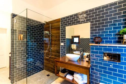 y baño de azulejos azules con lavabo y ducha. en Convent Franklin - Martina Unit, en Franklin