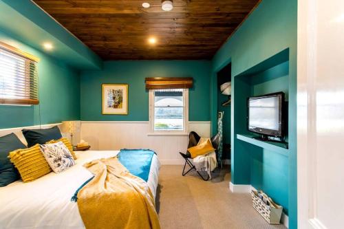 1 dormitorio con paredes verdes, 1 cama y TV en Convent Franklin - Martina Unit, en Franklin