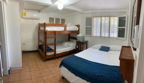 a bedroom with two beds and a bunk bed at Looking Good Surf House San Juan del Sur in San Juan del Sur