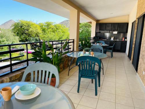 balcón con mesas y sillas y cocina en Pedregal Suites - Marina and Downtown en Cabo San Lucas