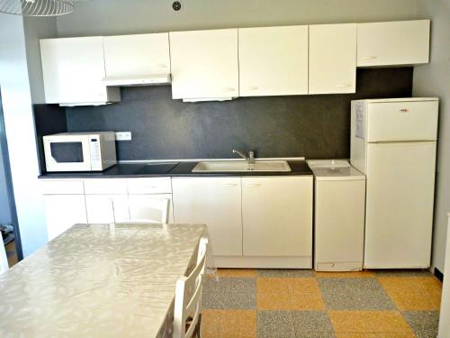 une cuisine avec des armoires blanches, un évier et un réfrigérateur dans l'établissement Appartement à 2 pas de la plage avec terrasse et parking - FR-1-387-150, à Marseillan