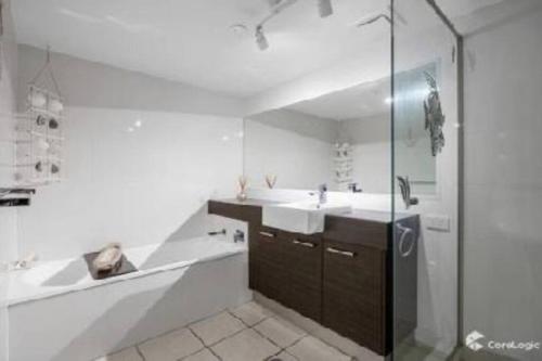 uma casa de banho com uma banheira, um lavatório e um chuveiro em Kawana Waters Ocean Front Unit- Sunshine Coast em Buddina
