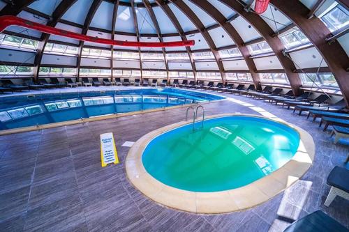 a large swimming pool in a building with a roof at Hotel Perla in Slănic-Moldova
