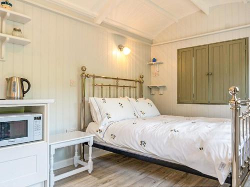 a bedroom with a bed and a microwave in it at Fig Tree Shepherds Hut in Bridport
