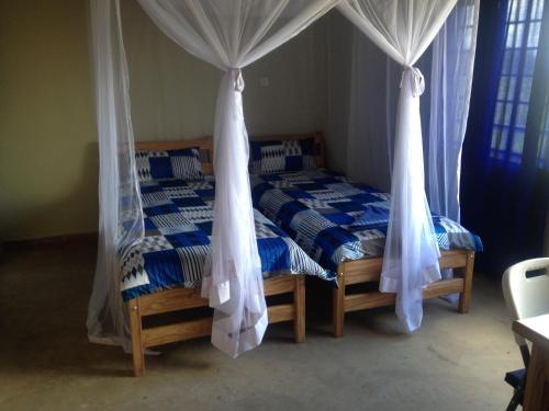 a bedroom with two beds with mosquito nets at Yellow Haven Lodge in Kampala