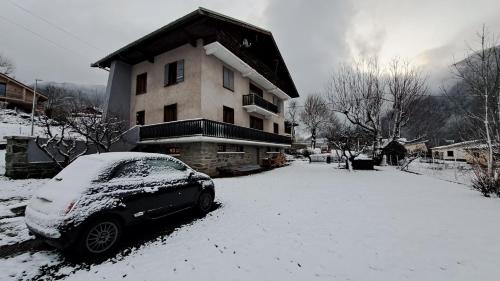 Tres bel appartement dans une maison avec SPA في Séez: سيارة متوقفة أمام منزل مغطى بالثلج