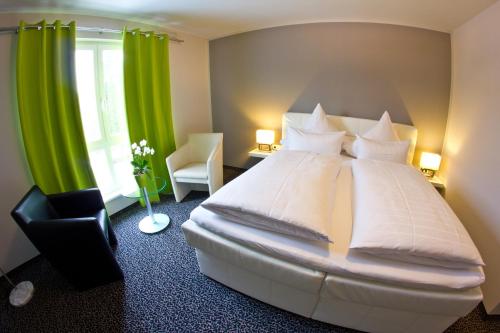 a bedroom with a large white bed with green curtains at Hotel Eyberg in Dahn