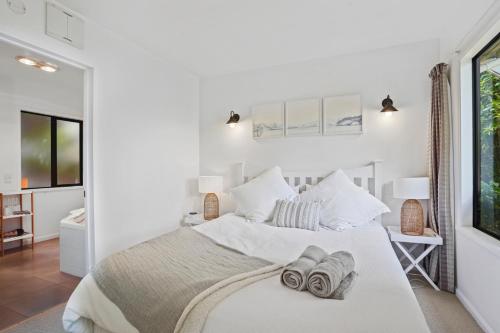 1 dormitorio con 1 cama blanca y 2 toallas en Bushside Cottage - Akaroa Holiday Home, en Akaroa