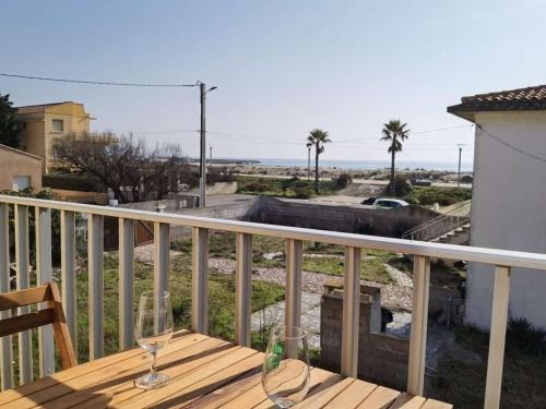 - un balcon avec 2 verres à vin sur une table en bois dans l'établissement Studio moderne, proche plage et commerces, terrasse ensoleillée - FR-1-326-699, à Marseillan