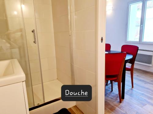La salle de bains est pourvue d'une douche et d'une table avec une chaise rouge. dans l'établissement Appartement calme et pratique., à Tours
